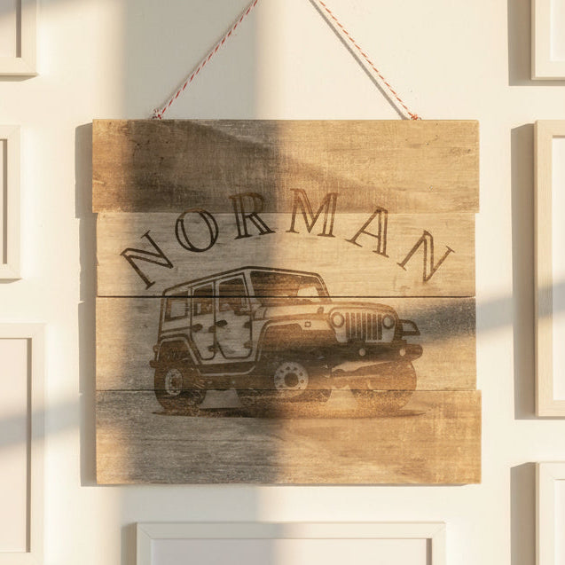 Wooden sign with 'Norman' and a jeep graphic on a wall.